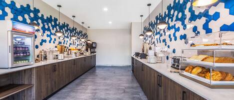 Ein modernes Café mit einer langen Theke, einer Kaffeemaschine und einer Vitrine voller Gebäck.