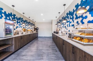 A modern cafe with a long counter, a coffee machine, and a display case with pastries.