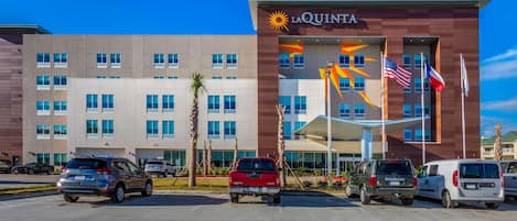 A hotel with a modern design, featuring a prominent 'La Quinta' sign and multiple flags.