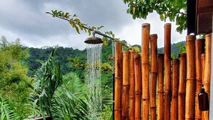 Una staccionata di bambù, un elemento d'acqua e una vegetazione lussureggiante.