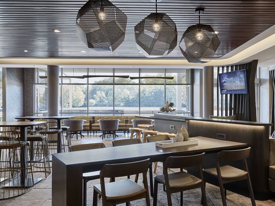 Un comedor moderno con lámparas colgantes hexagonales, un ventanal con vistas y un televisor de pantalla plana montado en la pared.