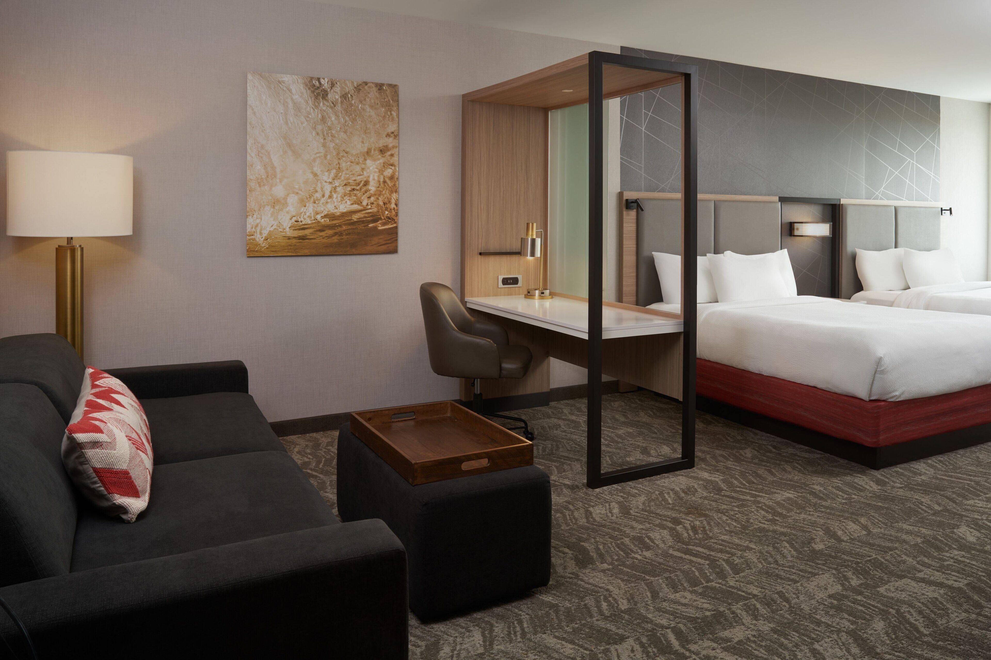 Une chambre d’hôtel comprenant un lit, un bureau, une chaise, un canapé et une lampe.