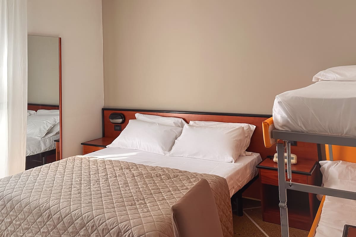 A hotel room with a large bed, a smaller bed, a nightstand, and a mirror.