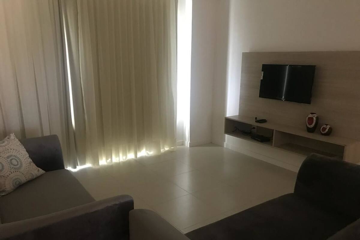 Un salon moderne avec un téléviseur à écran plat fixé au mur, un canapé et une table basse.