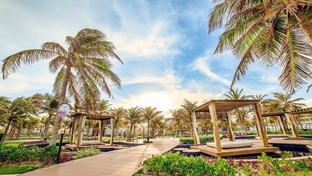 A resort with palm trees, wooden walkways, and outdoor seating areas. - Golf Ville Resorts Suites (Aquiraz)