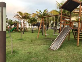 Un parque infantil con columpios, tobogán y una pequeña estructura para escalar.