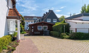 Un quartier résidentiel avec une allée pavée, une maison en bois dotée d’un garage et entourée d’autres maisons.