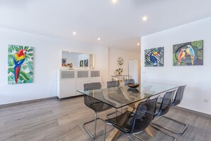 A modern dining area with a glass table and black chairs, surrounded by white walls and wooden flooring. - Central Apartment "Marbella Suites" Near the Beach with Pool, Terrace & Air Conditioning (Marbella, Málaga)