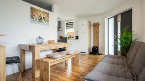 Una sala moderna con un banco de madera, un sofá gris y una mesa de comedor con un florero y un cuenco.