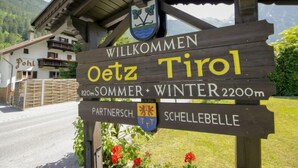 Un letrero de madera con el texto 'WILLKOMMEN Oetz Tirol' y 'Sommer Winter 2200m' que indica una ubicación en Oetz, Tirol, a una altitud de 2200 metros.