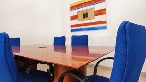 A conference room with a wooden table, blue chairs, and a colorful abstract painting on the wall. - BH Business Hotel Group (Reynosa)