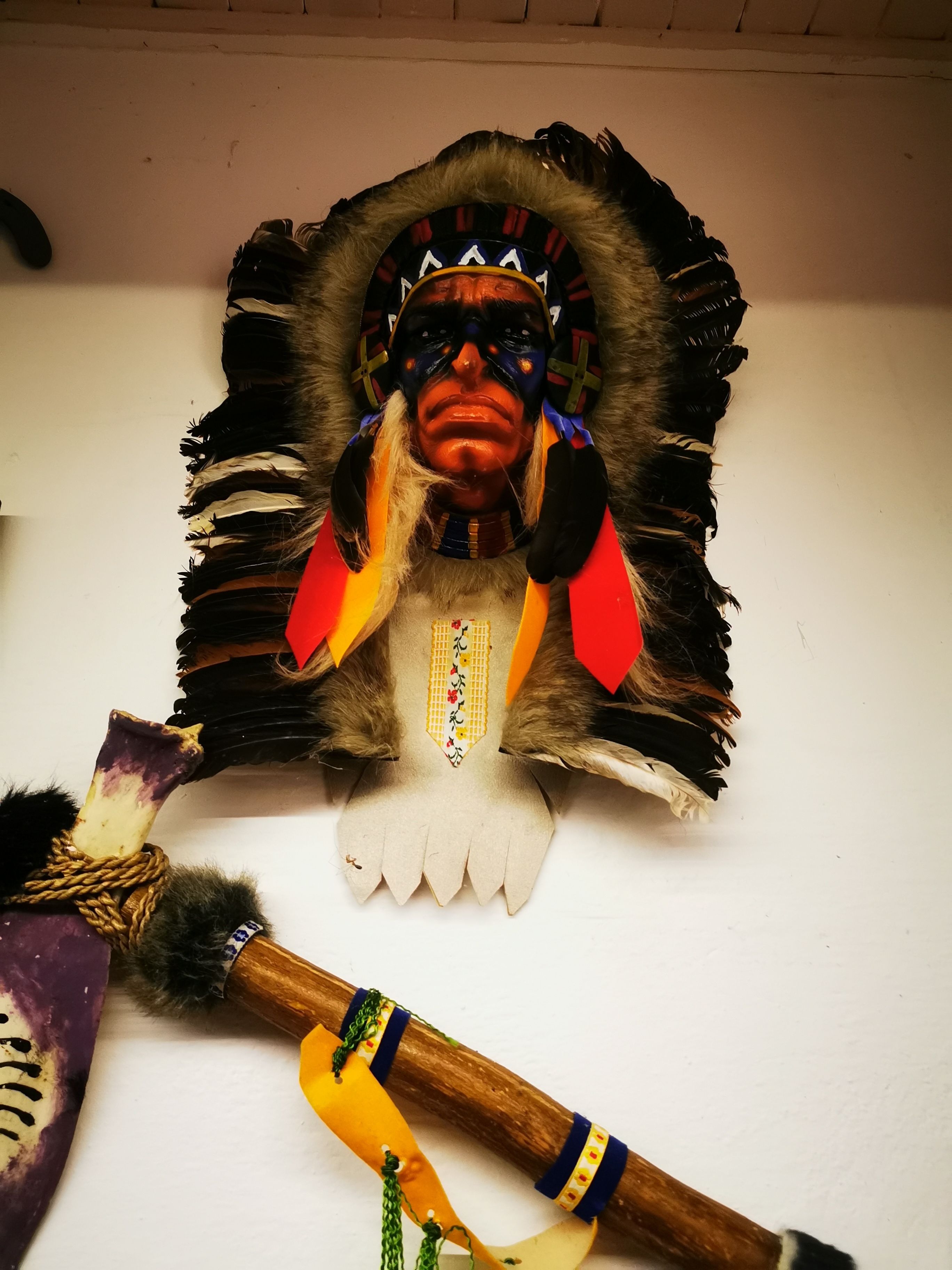 Eine geschnitzte Holzskulptur mit Kopfschmuck und Stab.