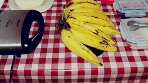 A table with food items and containers, a kettle, and a bed in the background. - Pousada Tia Cota (Barreirinhas)