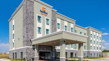 A Comfort Suites hotel with a stone facade, multiple windows, and a covered entrance.