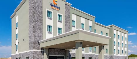 A Comfort Suites hotel with a stone facade, multiple windows, and a covered entrance.