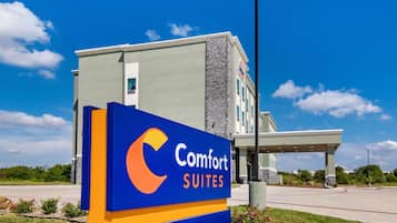 A Comfort Suites hotel sign with a modern building in the background.