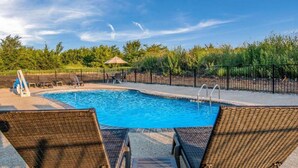 A swimming pool with lounge chairs and a fenced area, surrounded by trees and a clear sky. - Comfort Suites DeSoto Dallas South (DeSoto)