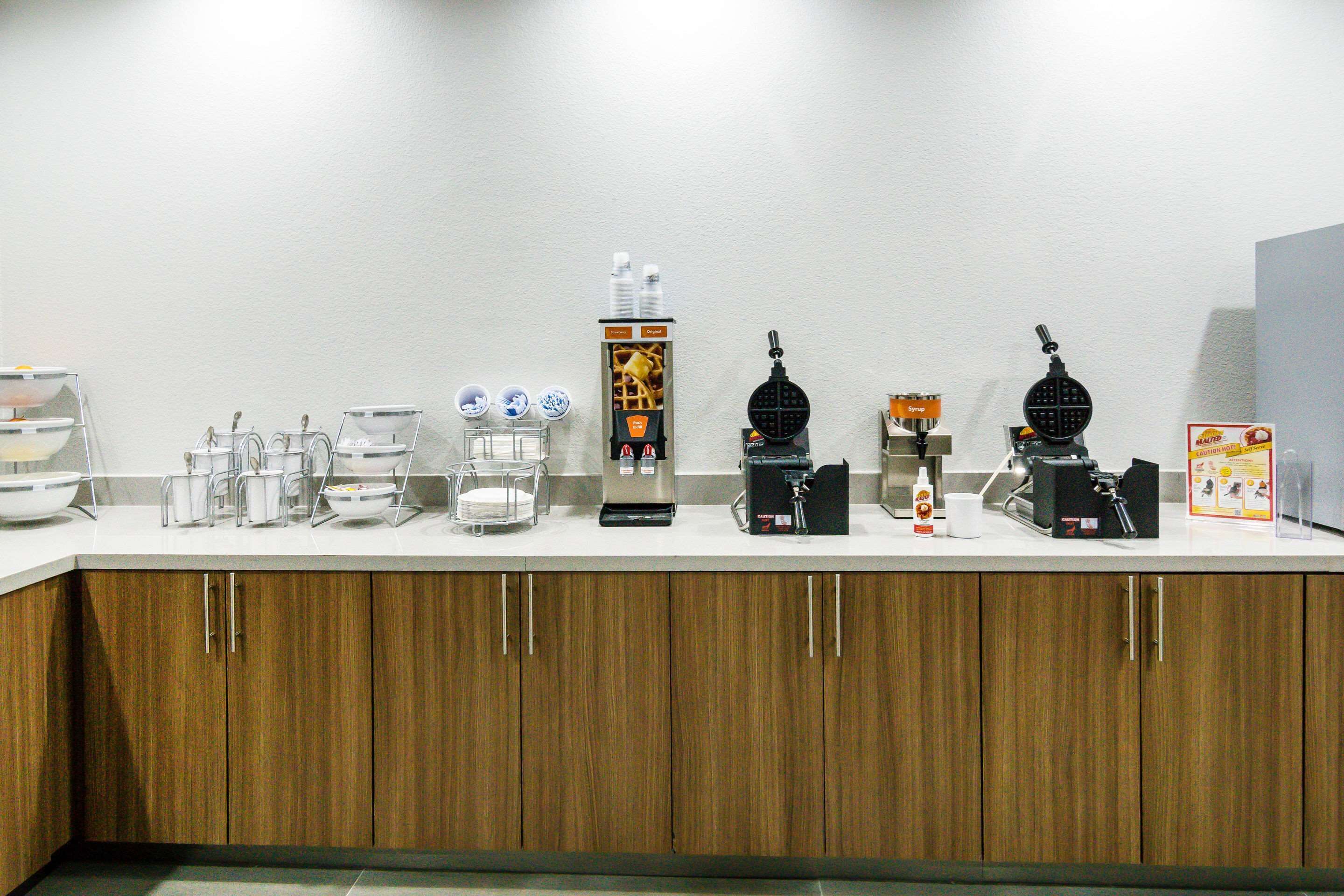 A kitchen counter with various appliances and utensils, including a coffee machine, a waffle maker, and a food processor.