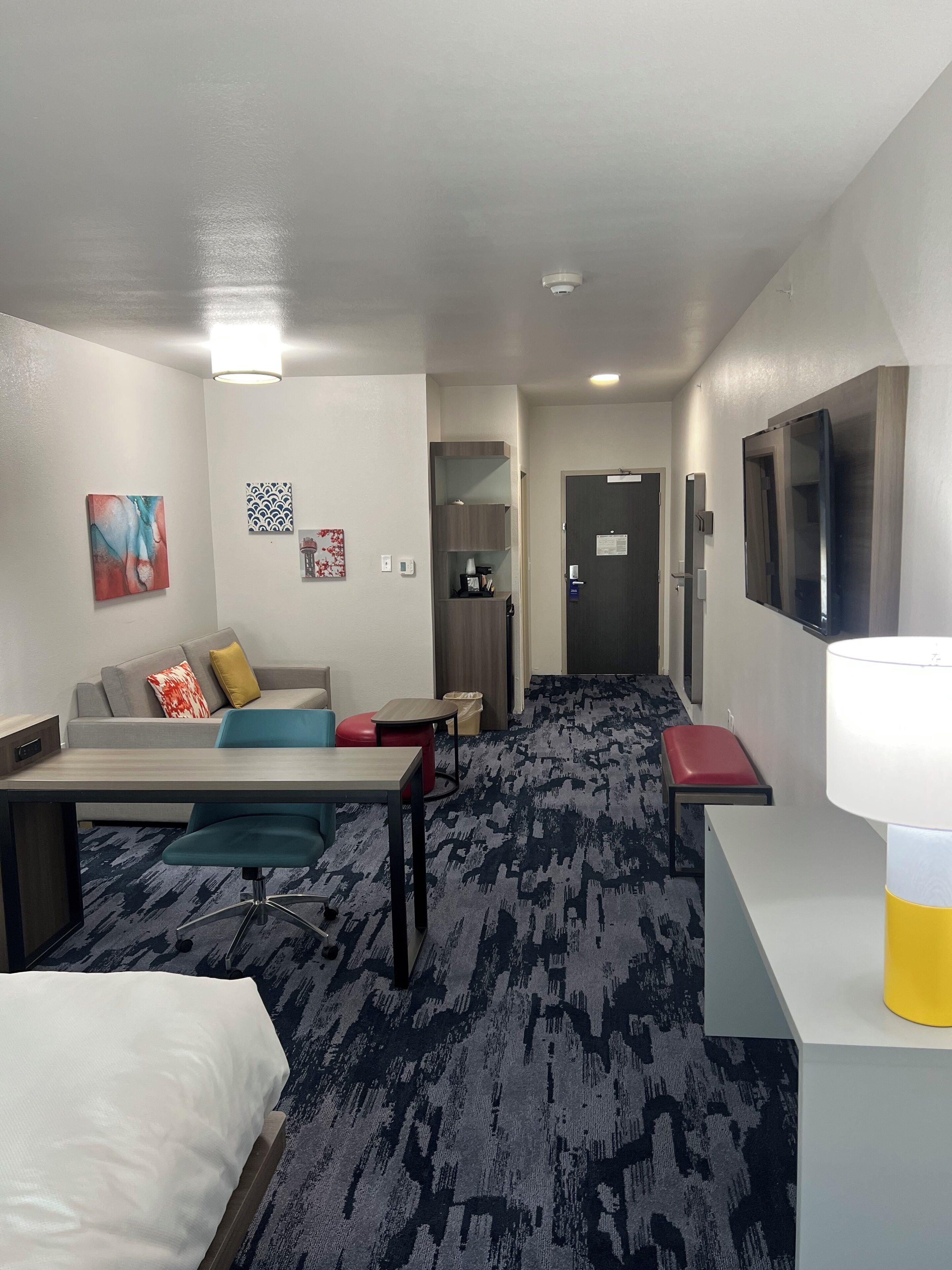 Een hotelkamer met een bed, een bureau, een bank, een televisie en een kleine tafel.
