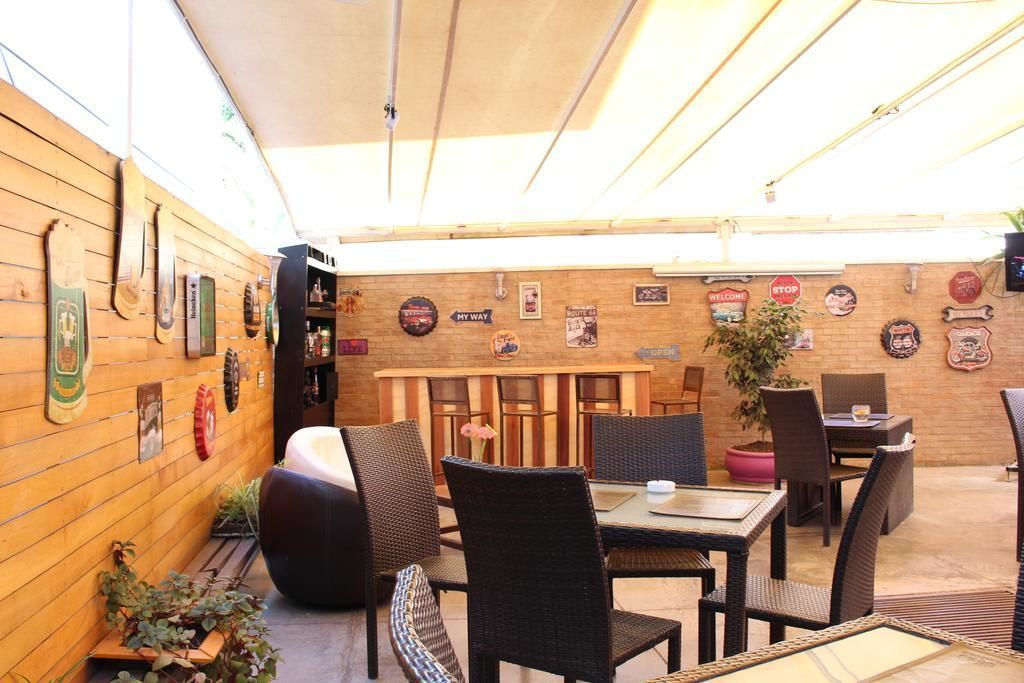 Un patio al aire libre con mobiliario de mimbre, una pared de madera con varios letreros y una planta en maceta.