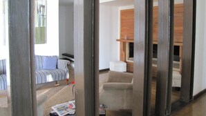 A living room with a striped sofa, a beige armchair, and a wooden cabinet. - Open Hotel (Quillota)