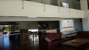 A spacious living area with a red sofa, a wooden coffee table, and a dining area with chairs and a table. - Senador Plaza Hotel (Senador Canedo)