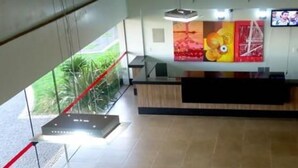 A modern hotel lobby with a reception desk, a large window with a view of greenery, and a seating area with a fire feature. - Senador Plaza Hotel (Senador Canedo)