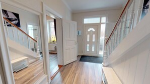 A hallway with a wooden floor, white walls, and a white door with glass panels. - Vacation home Friedrichstraße 16 (Laboe)
