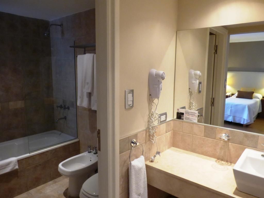 A bathroom with a bathtub, toilet, bidet, and a large mirror.