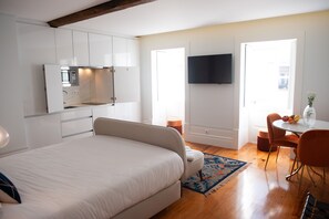 A modern bedroom with a large bed, a built-in kitchenette, a flat-screen TV, and a dining area with a table and chairs. - Guimarães IN (Guimarães)