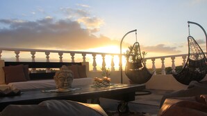 Un balcon avec un lit, des chaises suspendues et une statue de Bouddha.