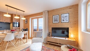A modern living room with a TV, seating, and a kitchen area with wooden cabinets and a dining table. - Pracondu 1 407 - OUTDOOR & FUN  apartment 6 pers (Haute-Nendaz)