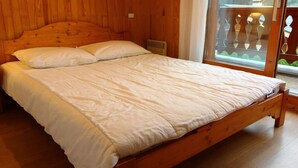 Ein hölzernes Bett in einem Zimmer mit einem großen Fenster und Blick auf Grün.