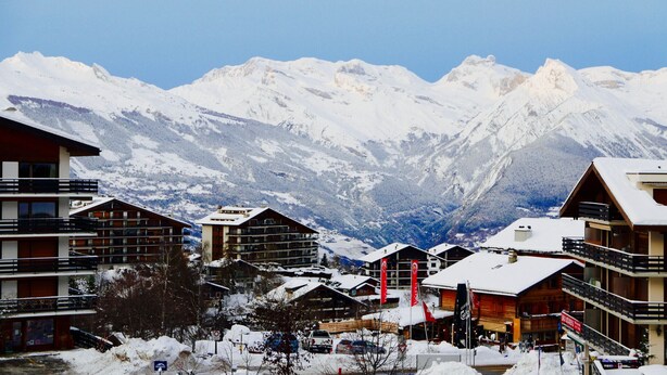 Ein schneebedecktes Bergresort mit mehrstöckigen Gebäuden, Skipisten und freiem Blick auf die Berge.