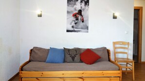 Ein Holzsofa mit drei Kissen, ein Holzstuhl und ein Wandbild eines Skifahrers.