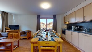 A compact living space with a dining table set for six, a sofa, a television, and a kitchen area with cabinets and appliances. - Pracondu 1 A01 - OUTDOOR & FUN  charming apartment (Haute-Nendaz)