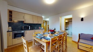 A compact kitchen with modern appliances, a dining area with wooden chairs and a table set for four, and a small living area with a sofa. - Pracondu 1 A01 - OUTDOOR & FUN  charming apartment (Haute-Nendaz)