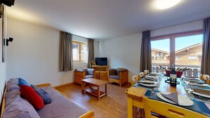 A cozy living room with a sofa, a TV, and a dining area set for a meal. - Pracondu 1 A01 - OUTDOOR & FUN  charming apartment (Haute-Nendaz)