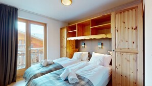 Een hotelkamer met twee bedden, houten lambrisering, een balkon en een houten garderobe.