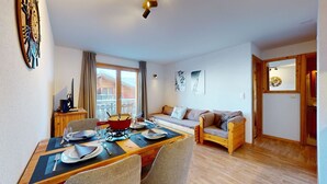 Een eethoek met een tafel voor twee personen, een bank en een raam met gordijnen.