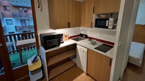 Cozinha compacta com armários de madeira, micro-ondas, pia e lava-louças.