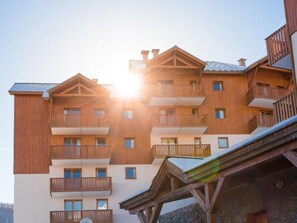 Un edificio de madera de varios pisos con balcones y una pista de esquí.