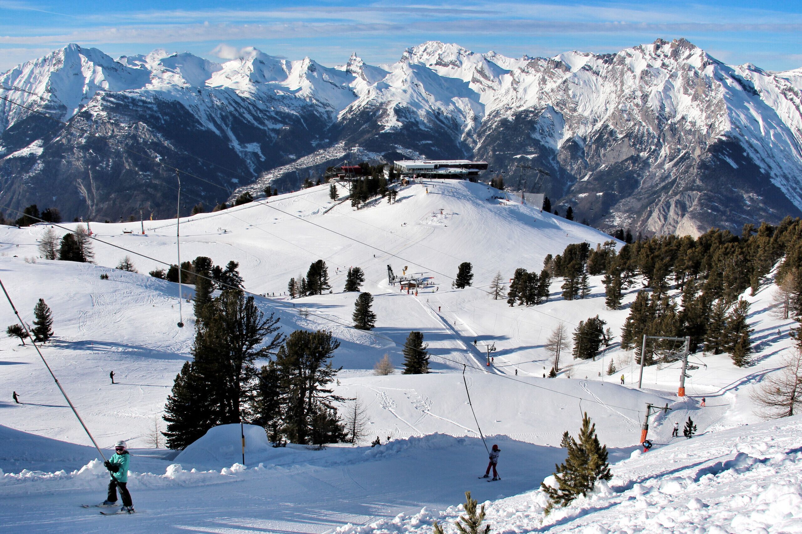 A ski resort with a chairlift, snow-covered slopes, and a mountain backdrop.