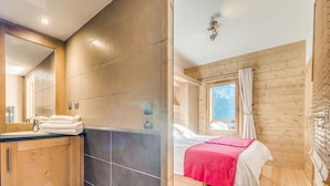 Un baño moderno con un espejo grande, un lavamanos y un inodoro. La habitación tiene paredes de madera y una ventana con cortinas.