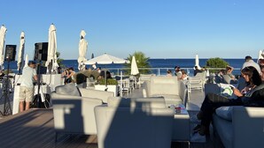 Un espace extérieur aménagé avec des chaises blanches dotées de coussins et des parasols, offrant une vue sur une étendue d’eau.