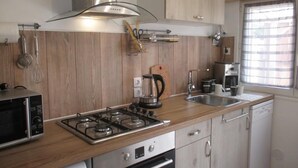 Een kleine keuken met een gasfornuis, een magnetron en een koffiezetapparaat.