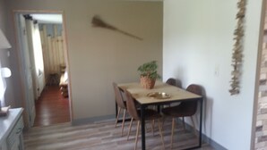 Een eetgedeelte met een tafel, stoelen, een plant en een decoratieve wandversiering.