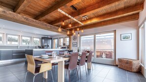 Une cuisine moderne dotée d’un grand îlot central, de poutres en bois au plafond et de grandes fenêtres.