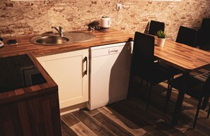 Une cuisine compacte équipée d’un évier, d’un lave-vaisselle et d’une table à manger en bois avec des chaises.