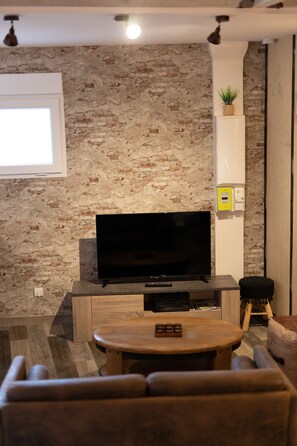 Een woonkamer met een flatscreen televisie, houten meubels en een bakstenen muur.